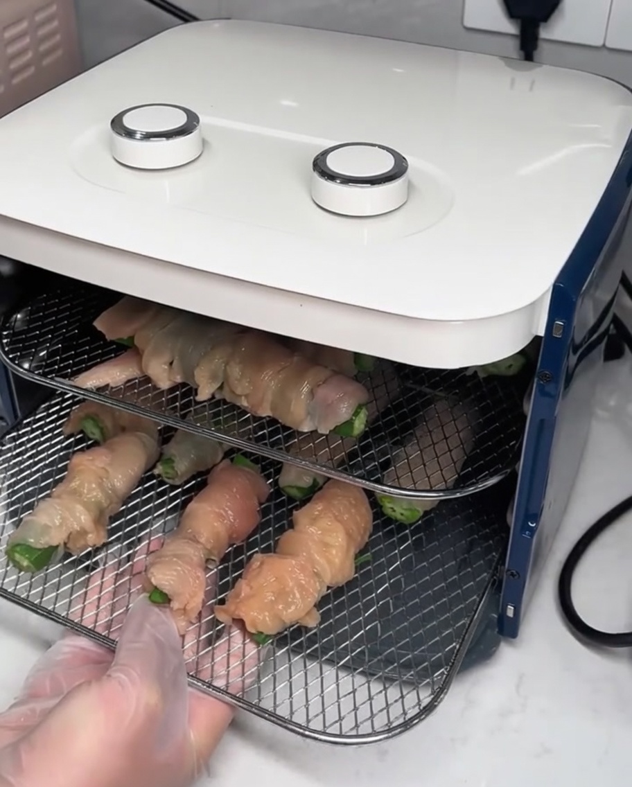 Drahtgitter mit den Wraps werden in einen Dörrautomaten geschoben.