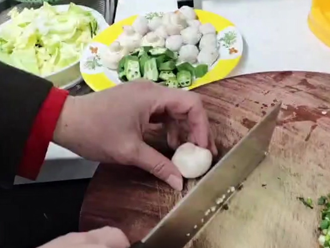 Weiße Champignons werden auf einer Holzunterlage in kleine Stücke gewürfelt.