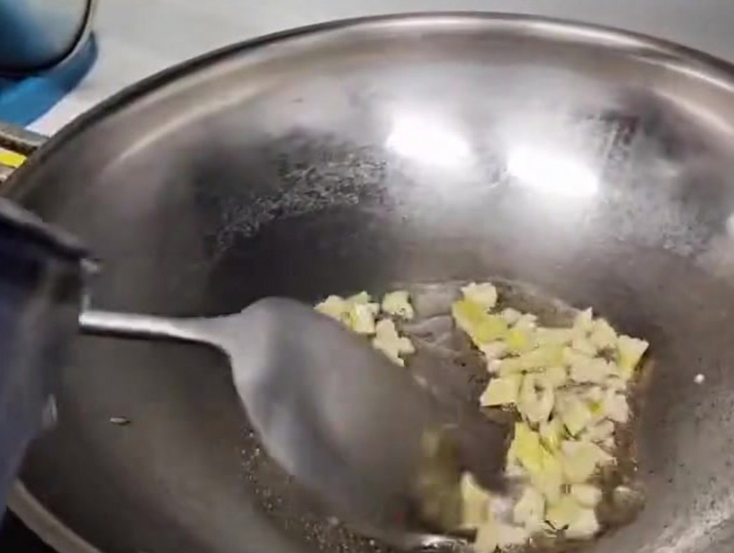 Wasser wird in einen Metall-Wok gegossen, um die Basis der Pilzsuppe zu bilden.