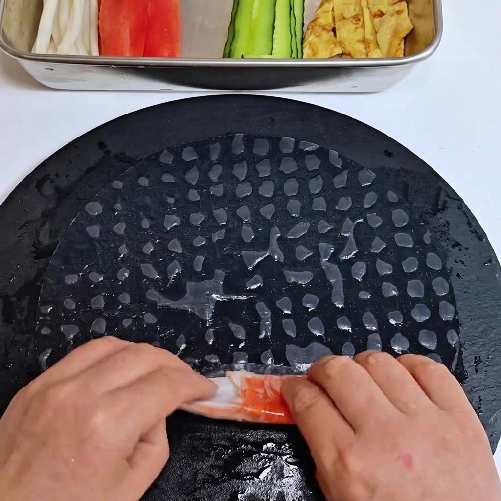 Surimi-Stücke werden in ein Reispapierblatt eingewickelt.