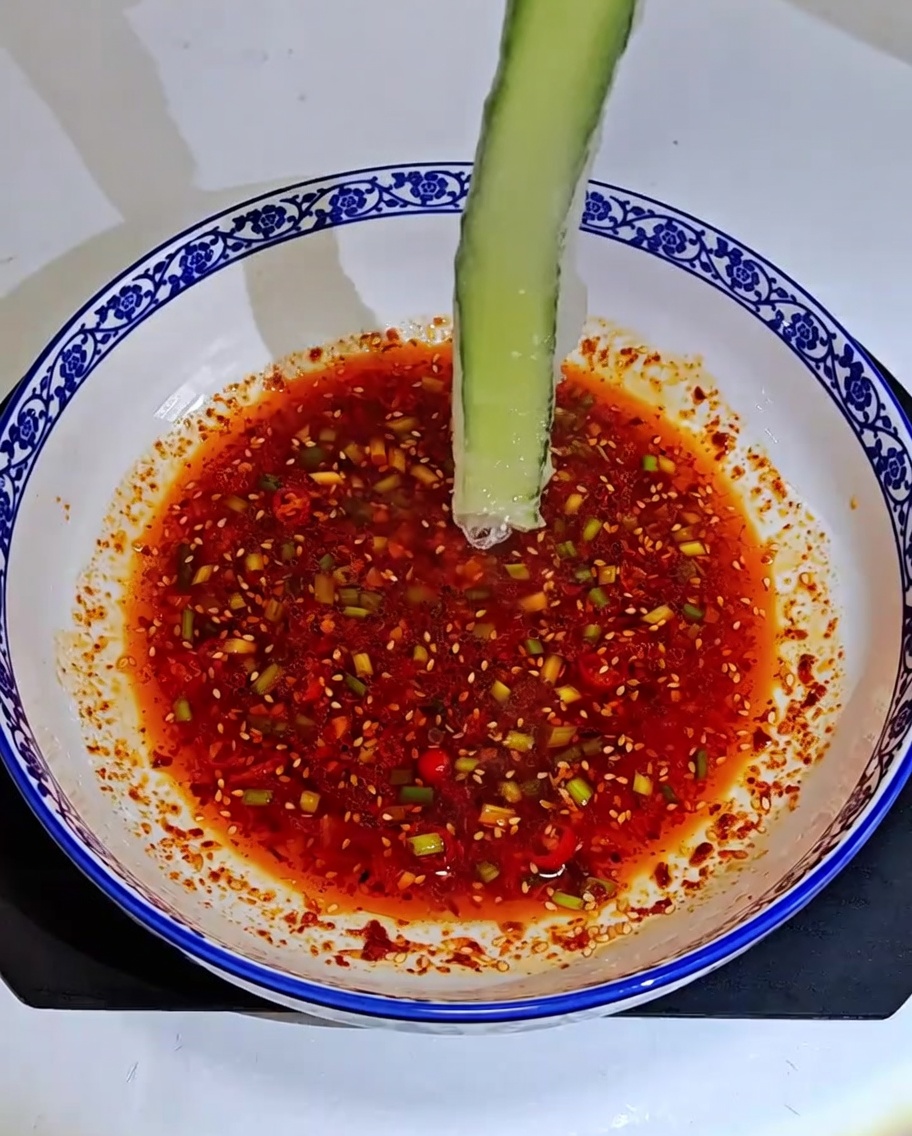 Gurken- und Surimi-Rollen liegen in einer gemusterten Schüssel in der Saucenmischung.