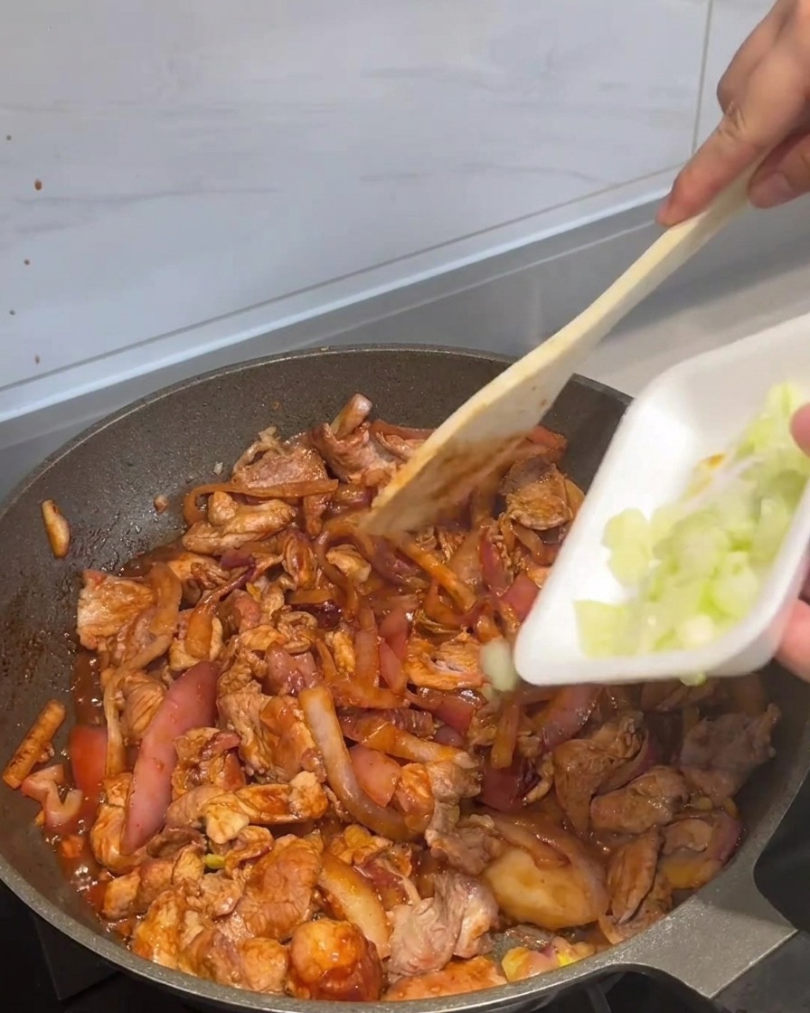 Die fertige Pfanne wird mit frischen Frühlingszwiebeln garniert.