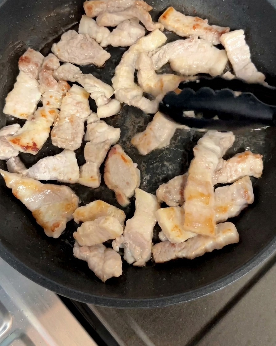 Schweinebauchstücke werden in der Pfanne gewendet, bis sie goldbraun sind.