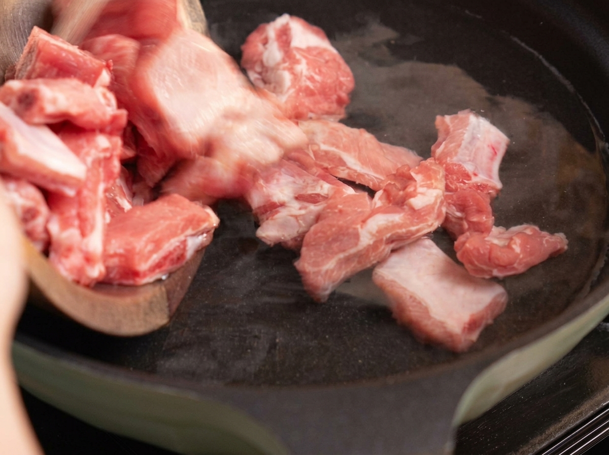 Schweinerippchen werden in einem Topf mit Wasser, Ingwer und Frühlingszwiebeln blanchiert.