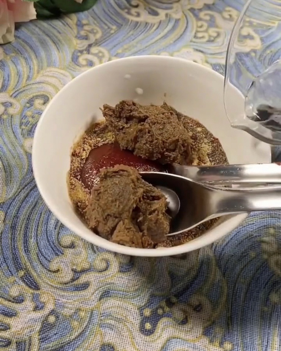 Nahaufnahme einer weißen Schüssel mit koreanischer Chilipaste und Sojabohnenpaste, während frisches Wasser zum Verdünnen hinzugefügt wird.