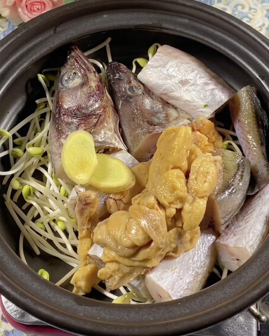 Frische Ingwerscheiben und Pollackrogen, platziert über Fischstücken in einem Topf.