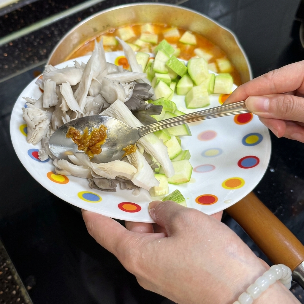 Zucchini und Pilze werden in den Topf gegeben.