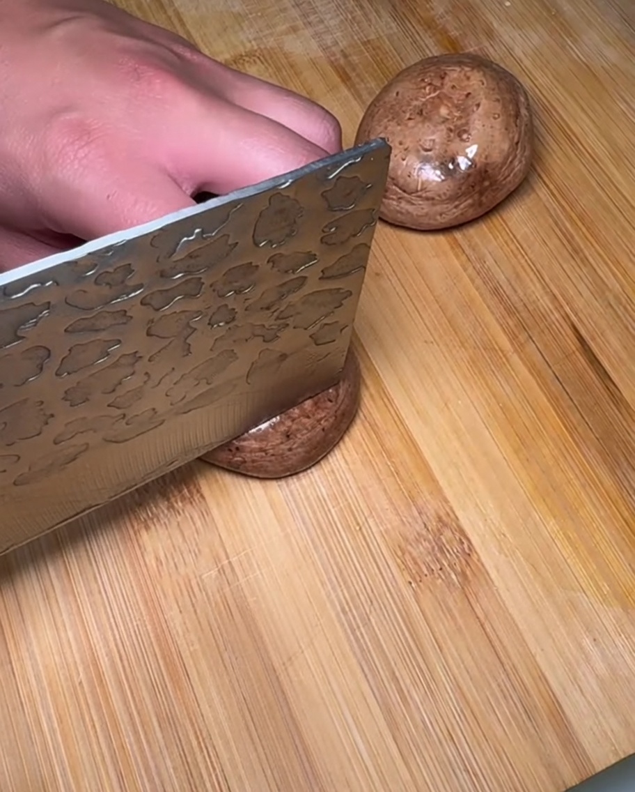 Frisch geschnittene Shiitake-Pilzstreifen auf einem Holzbrett.