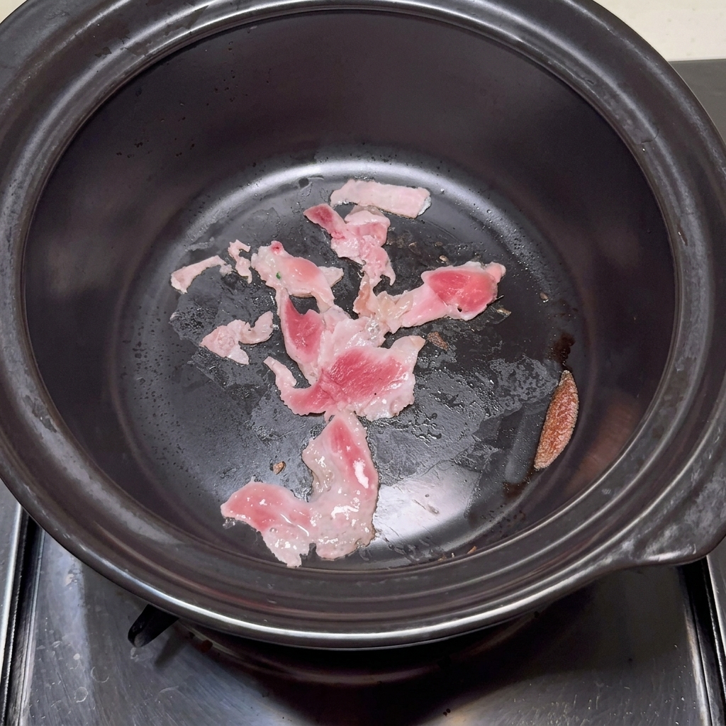 Klares Wasser wird in den Tontopf mit angebratenem Schweinebauch gegossen.