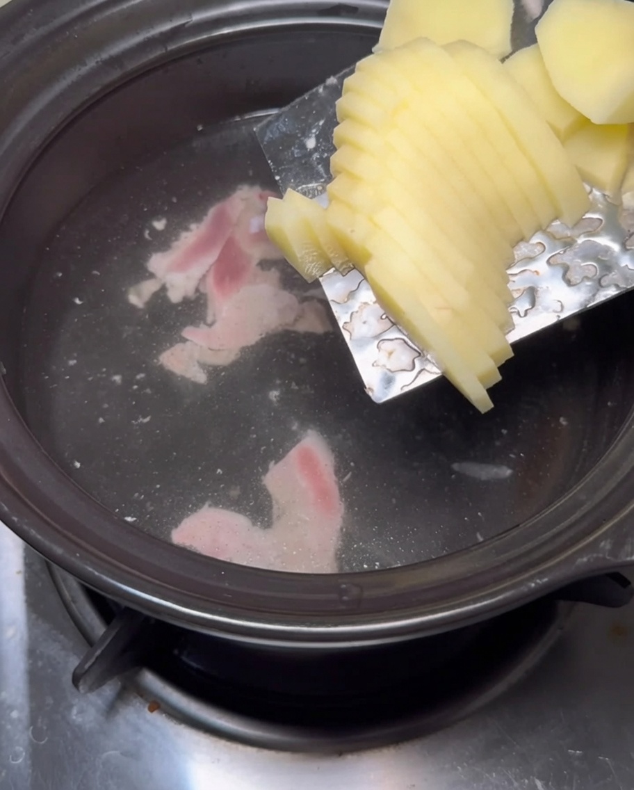 Kartoffelscheiben werden in die kochende Brühe gegeben.
