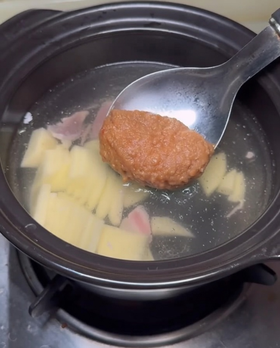 Löffel mit Sojabohnenpaste wird in die Brühe gerührt.