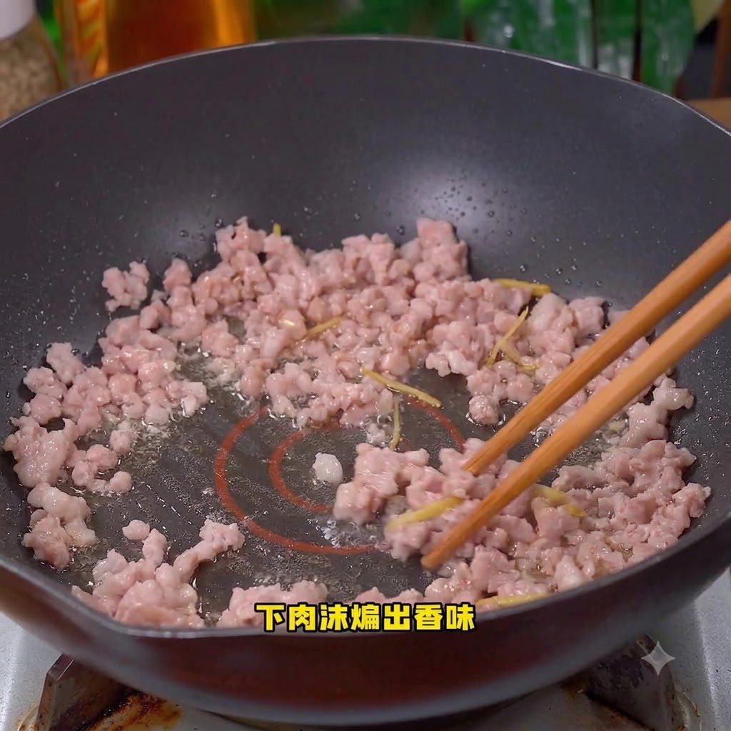 Schweinehackfleisch wird im Wok angebraten und umgerührt.