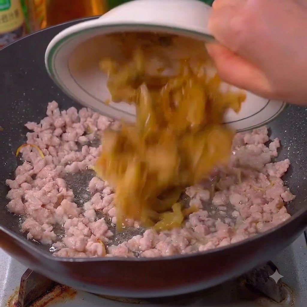 Saurer Senfkohl wird in den Wok zum Fleisch gegeben.