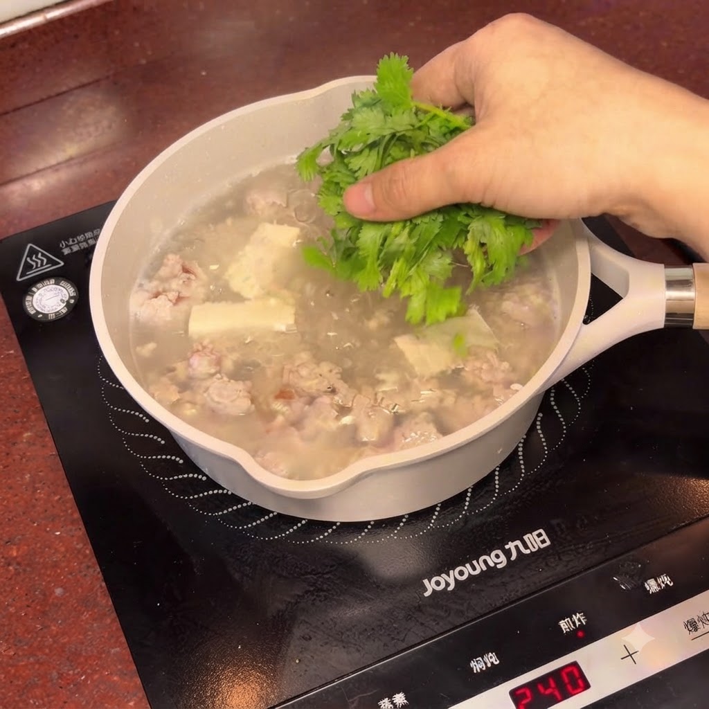 Frisch gehackter Koriander wird über den dampfenden Topf mit der Salzpflaumen-Tofu-Suppe gestreut.