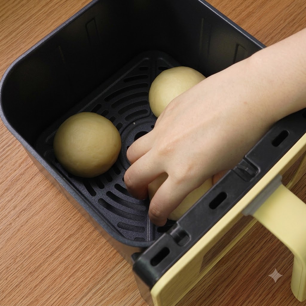 Drei geformte Teigbällchen ordentlich im Korb der Heissluftfritteuse angeordnet.