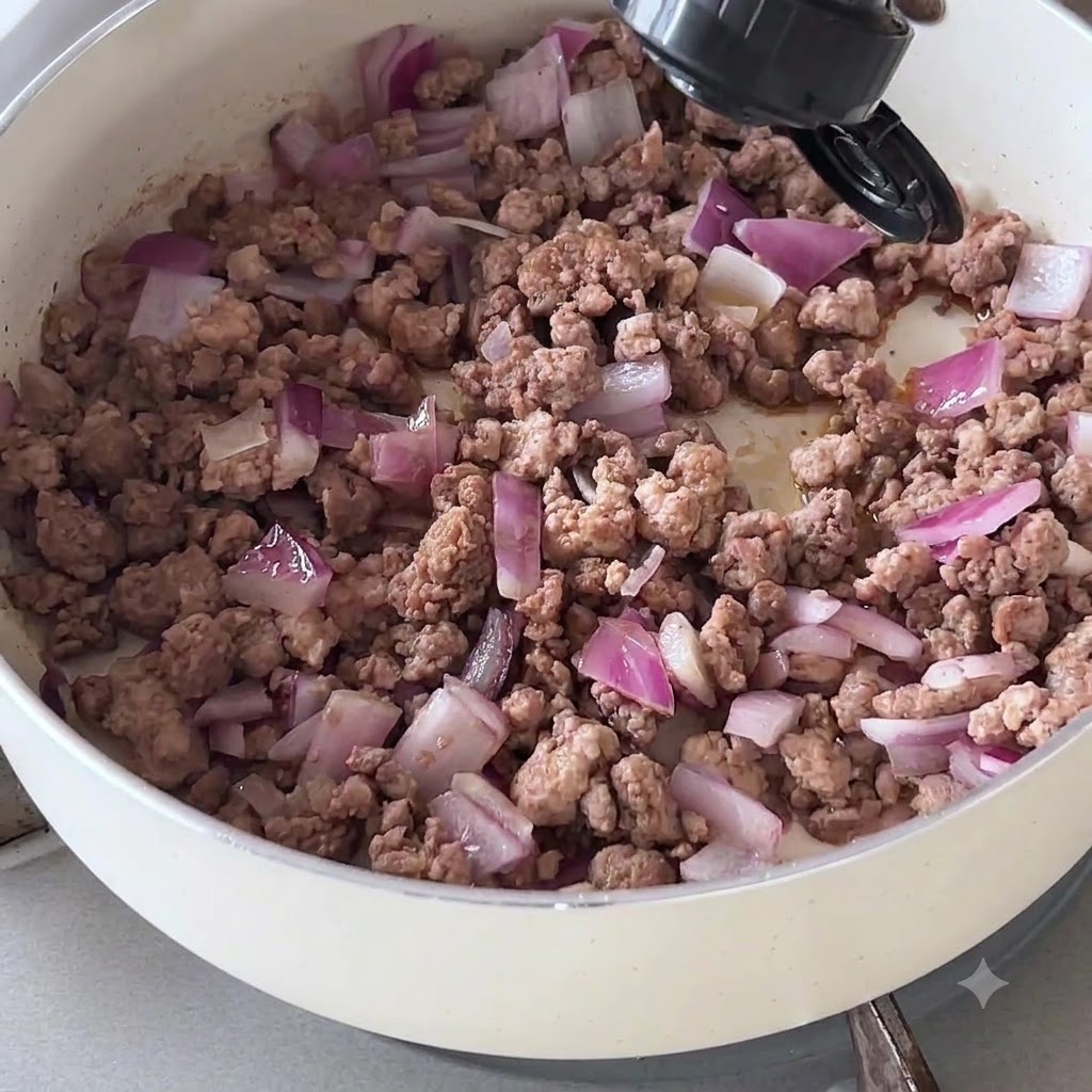 Dunkle Soße wird aus einer Flasche auf gekochtes Hackfleisch und Zwiebeln in einer Pfanne gegossen.