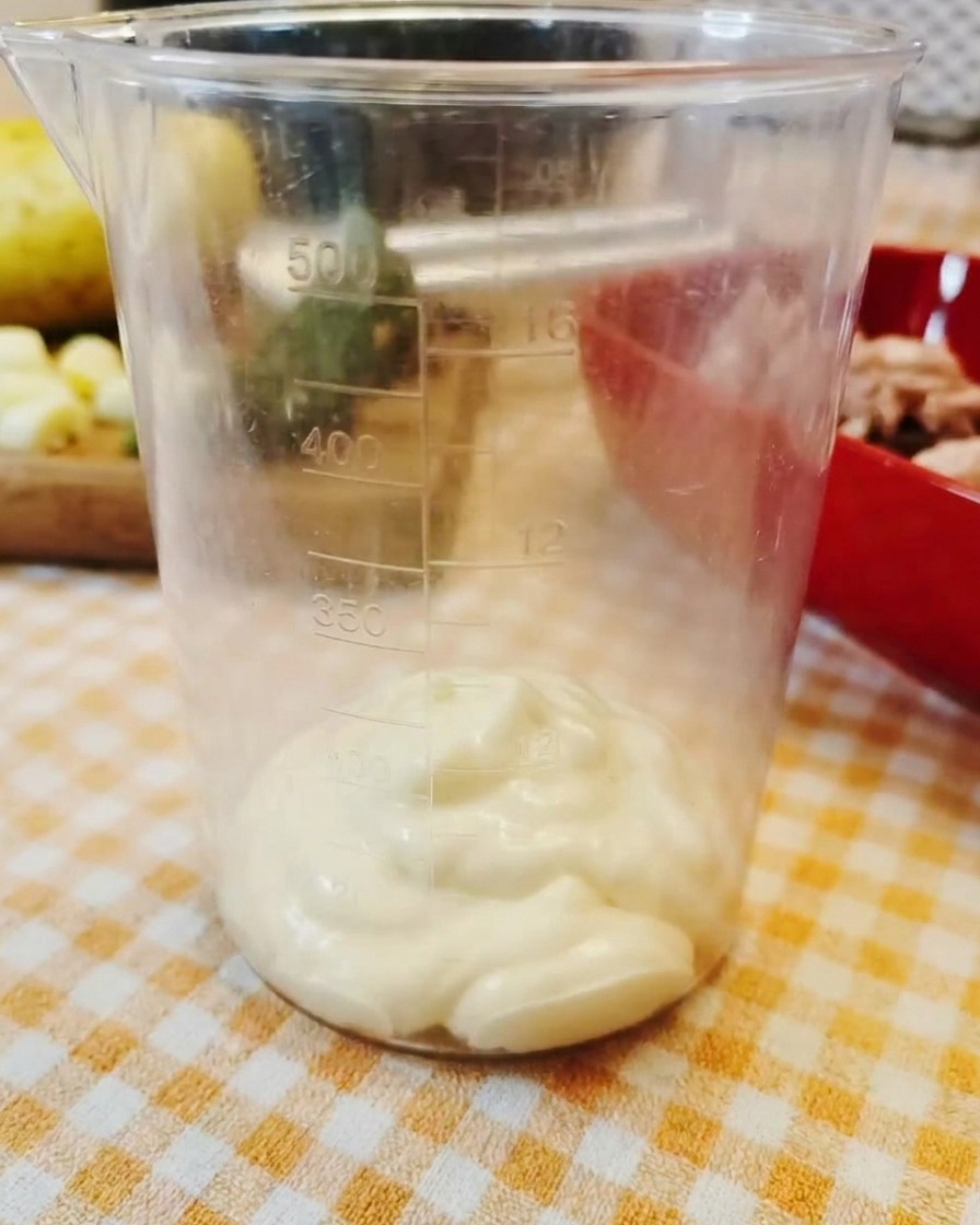 Ein Klecks dicke Mayonnaise am Boden eines klaren Messbechers.