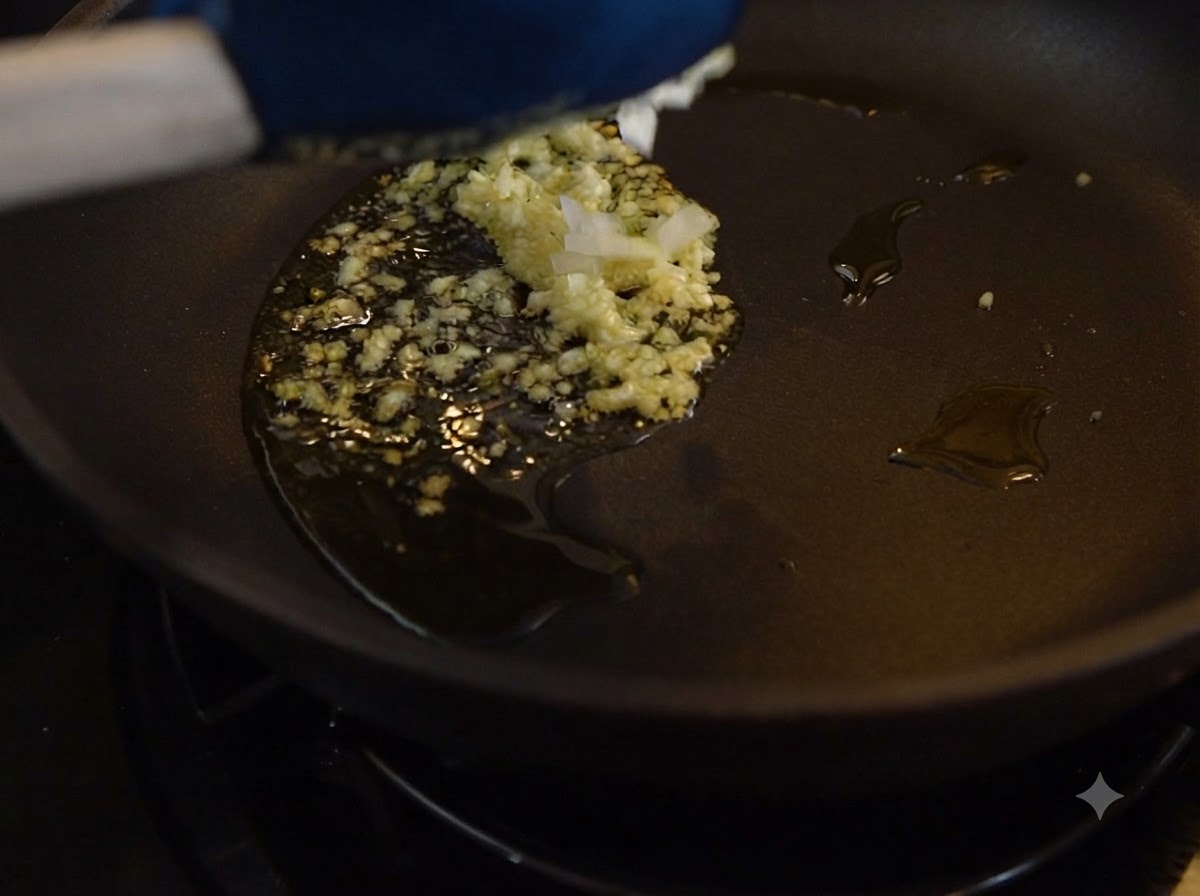 Gehackter Knoblauch und Zwiebeln braten in Öl in einer dunklen Pfanne.