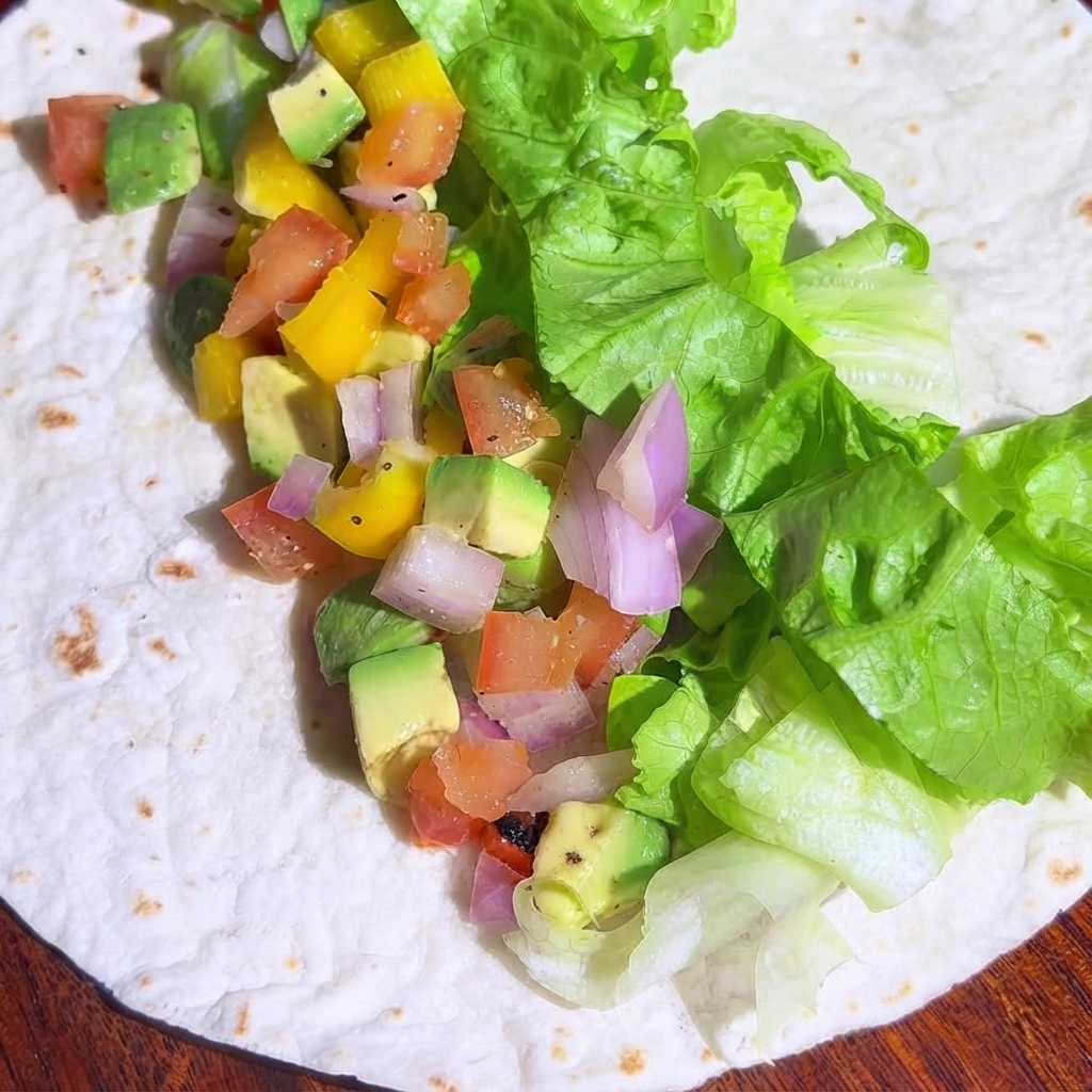 Gewürfelte, gebratene Hähnchenstücke verteilen sich über die Gemüsefüllung auf der Tortilla.