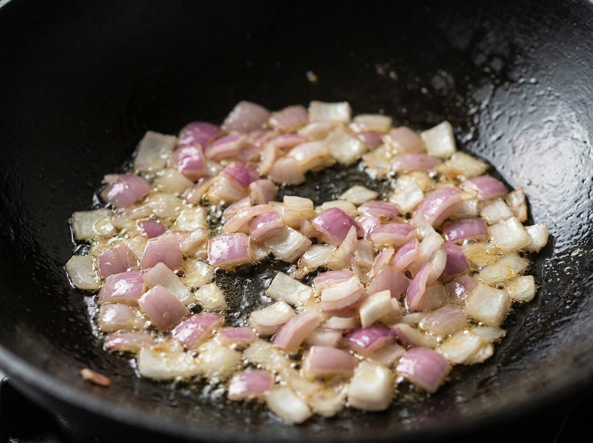 Gewürfelte rote Zwiebeln und Speck brutzeln und garen in Öl in einem schwarzen Wok.