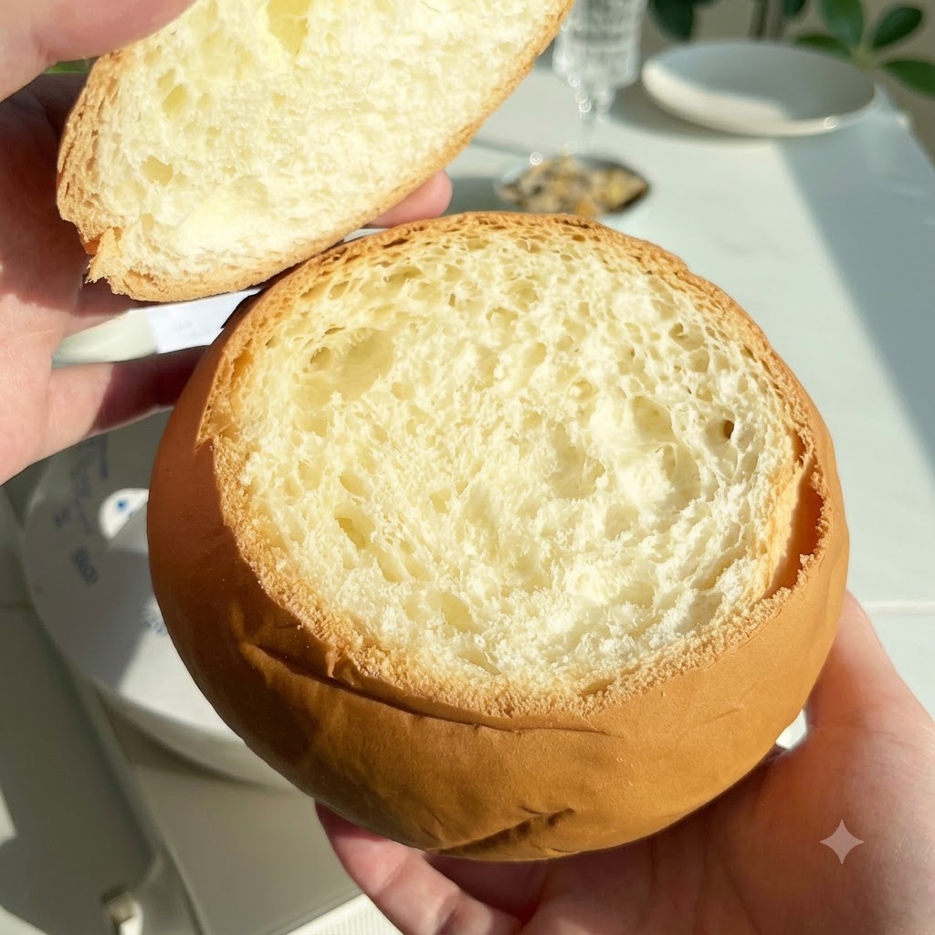 Ein ausgehöhlter runder Brotlaib mit abgenommenem Deckel daneben.