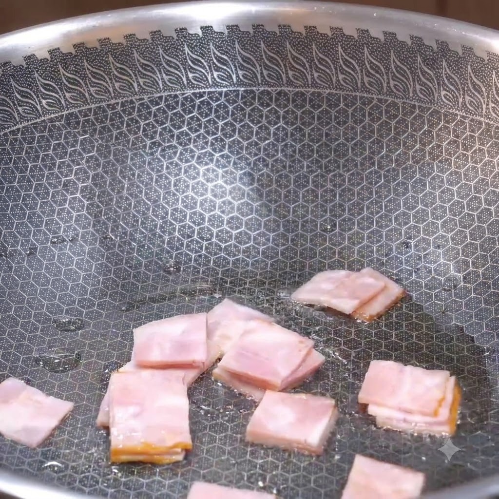 Quadratische Speckstücke werden in einem strukturierten Wok angebraten, bis sie braun werden.