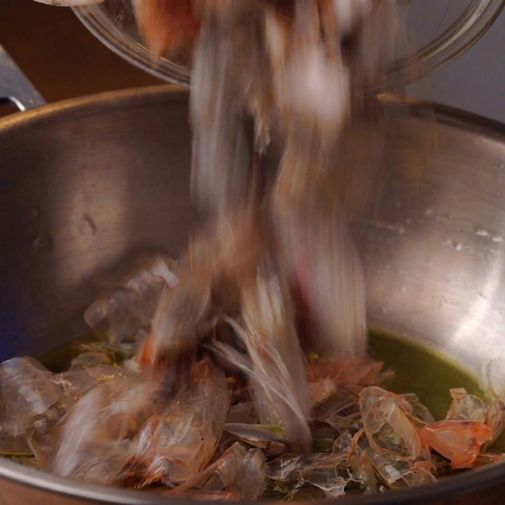 Garnelenköpfe braten in Öl in einem tiefen Metalltopf.