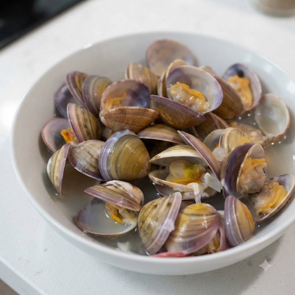 Ein kleiner Löffel gibt weißes Salz in eine weiße Schüssel gefüllt mit cremiger Muschelsuppe und geöffneten Muscheln.