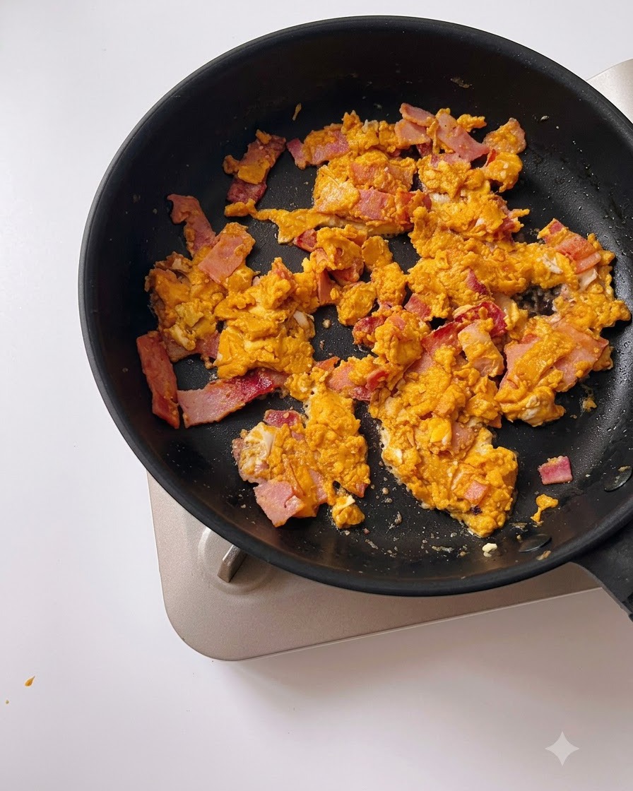 Wasser wird aus einem Messbecher in eine schwarze Pfanne mit gesalzenem Eigelb und Speck gegossen.