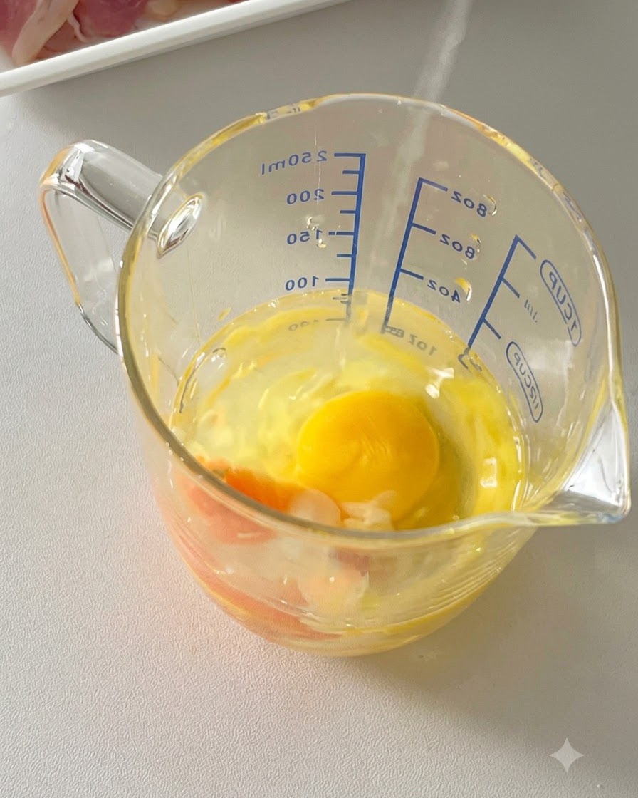 Eier, geriebener Parmesan und schwarzer Pfeffer kombiniert in einem Glasmessbecher.