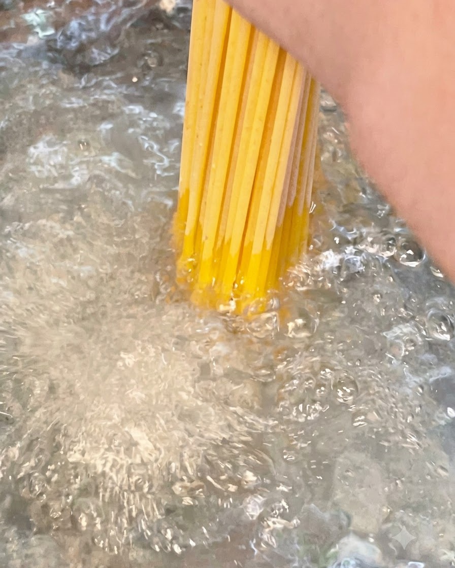 A bundle of dry long spaghetti noodles being submerged into a pot of actively boiling salted water.