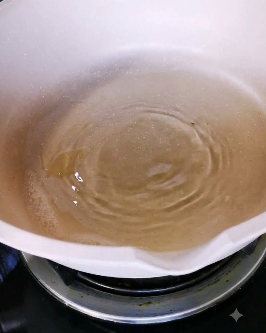 Olivenöl wird in eine weiße Keramikpfanne auf einer Herdplatte gegossen.