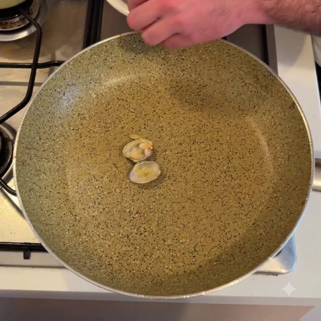 Muschelfleisch wird über einer leeren Bratpfanne aus der Schale gelöst.