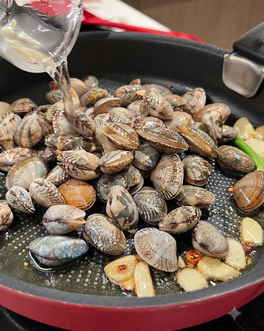 Trockener Weißwein wird aus einem klaren Gefäß über eine mit frischen Muscheln gefüllte Pfanne gegossen.