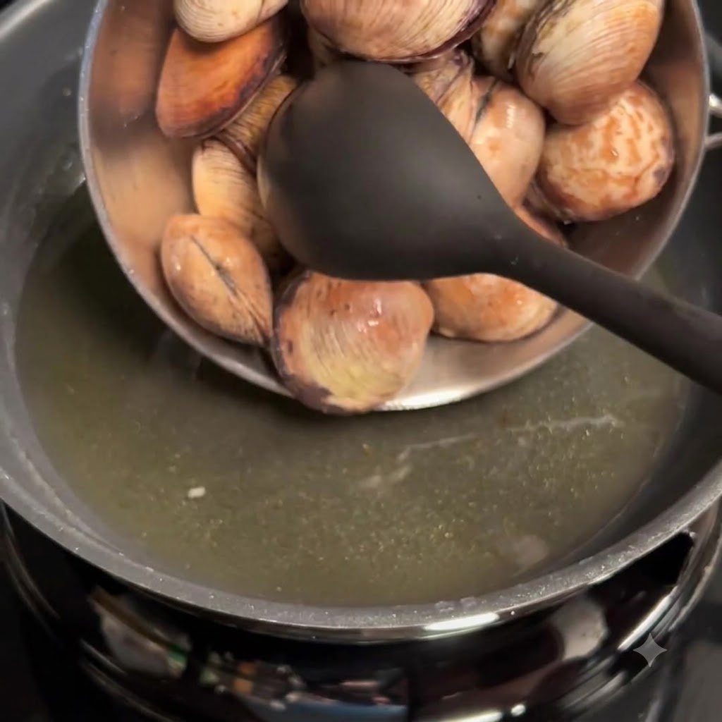 Gereinigte Muscheln werden aus einer Schüssel in eine Pfanne mit Knoblauchöl gegeben.