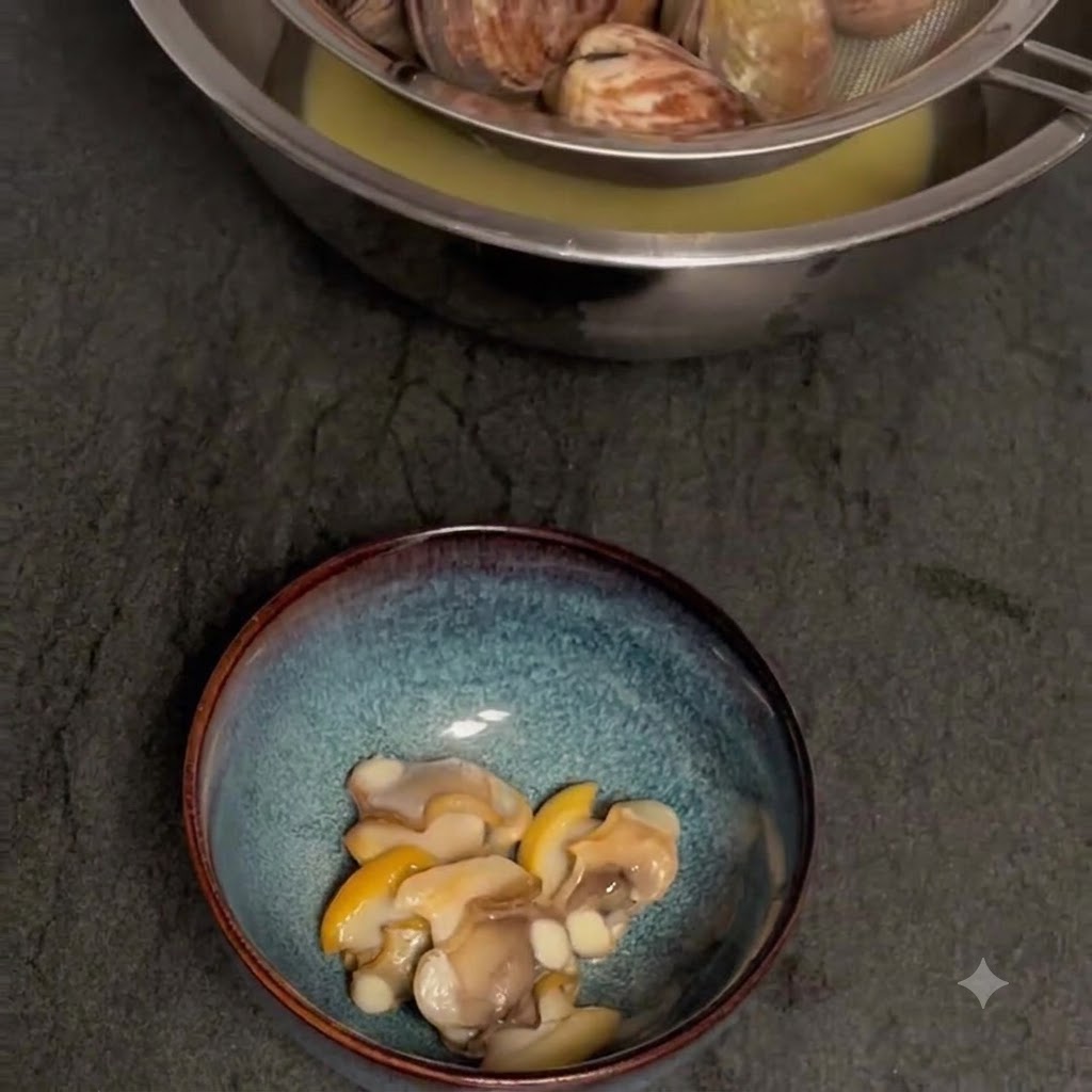 Gekochte Muscheln werden über einer Schüssel abgeseiht, um die Brühe aufzufangen, wobei sich das Muschelfleisch in einer separaten Schüssel darunter befindet.