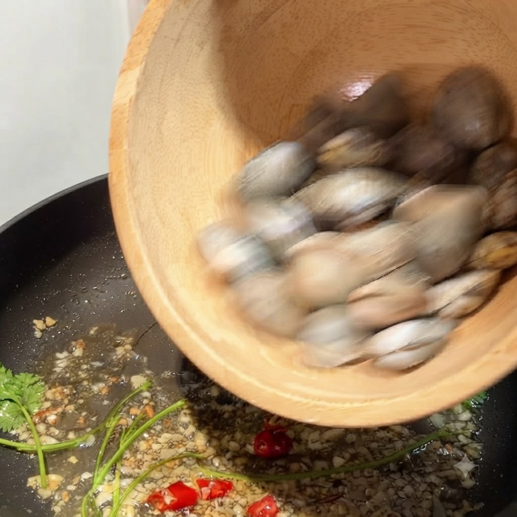Muscheln werden aus einer Holzschüssel in eine Pfanne mit angebratenem Knoblauch und Chili geschüttet.