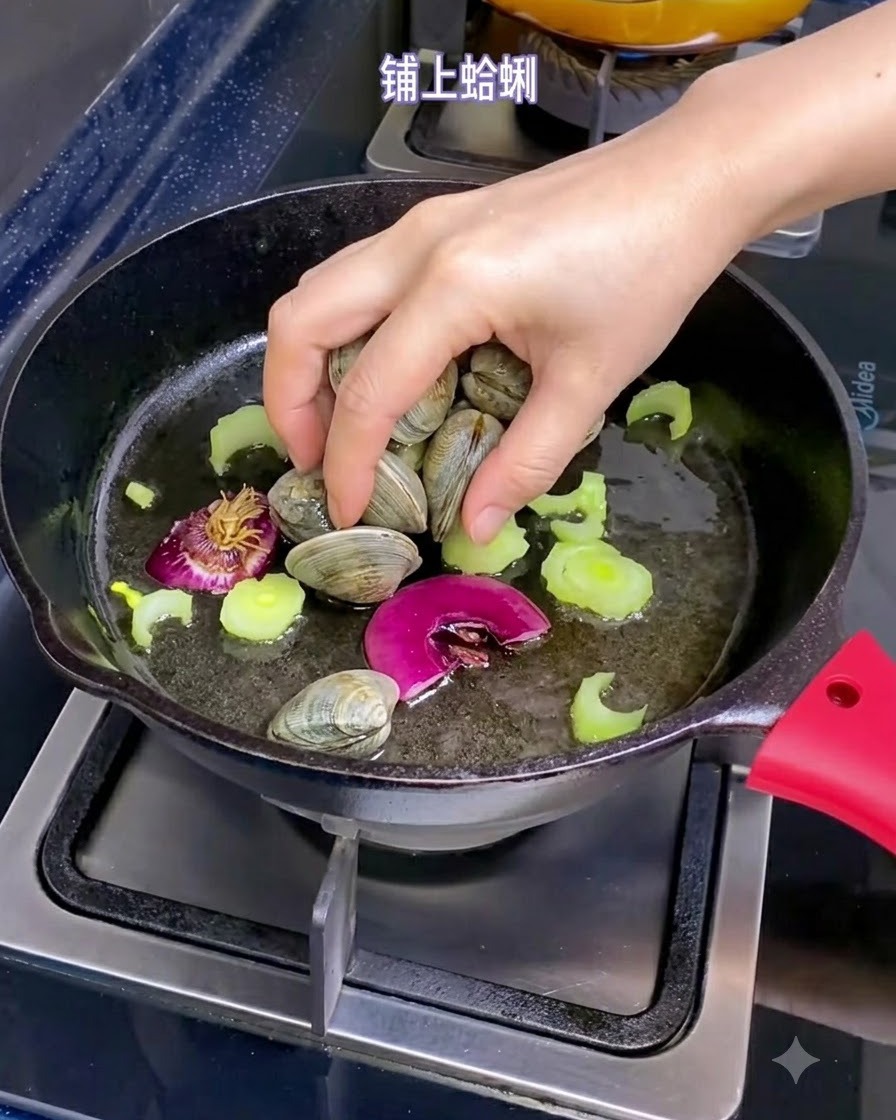 Eine Hand legt frische Muscheln in eine Pfanne gefüllt mit Olivenöl, Schalottenstücken und geschnittenem Sellerie.