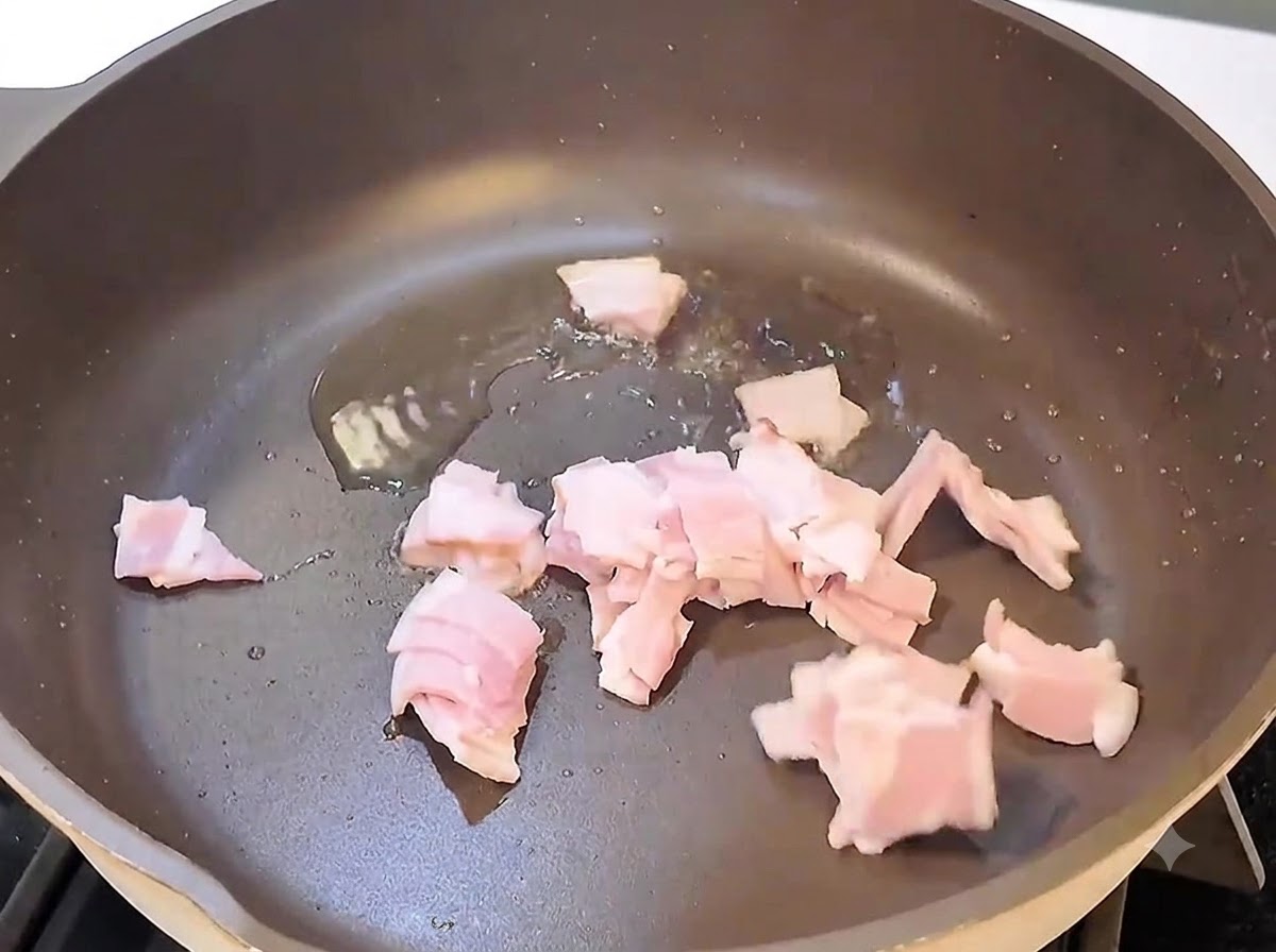 Speckstücke brutzeln und braten in einer schwarzen Pfanne über Hitze.