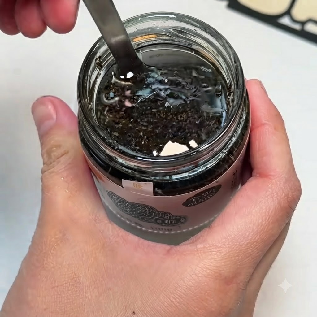 Eine kleine Schüssel mit schwarzer Trüffelsoße, Eigelb und Salz, die mit einem Löffel glattgerührt werden.