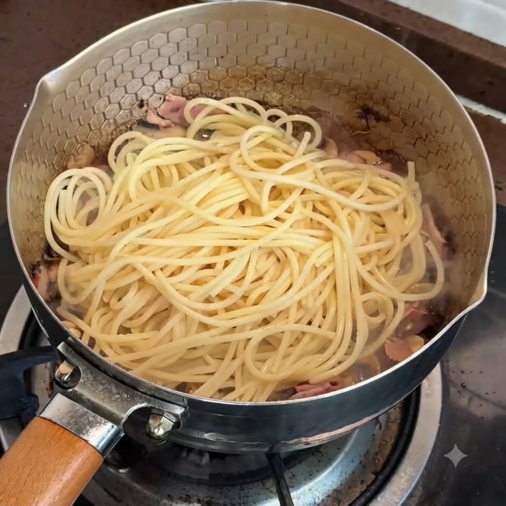 Pasta in einer Pfanne bereit zum Vermengen mit der Trüffel-Eigelb-Soße.