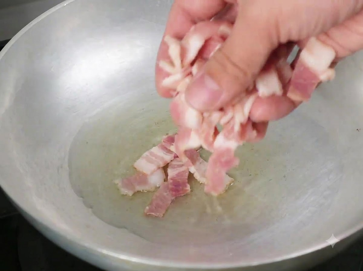 Speckstücke werden in eine Pfanne mit heißem Olivenöl gegeben.