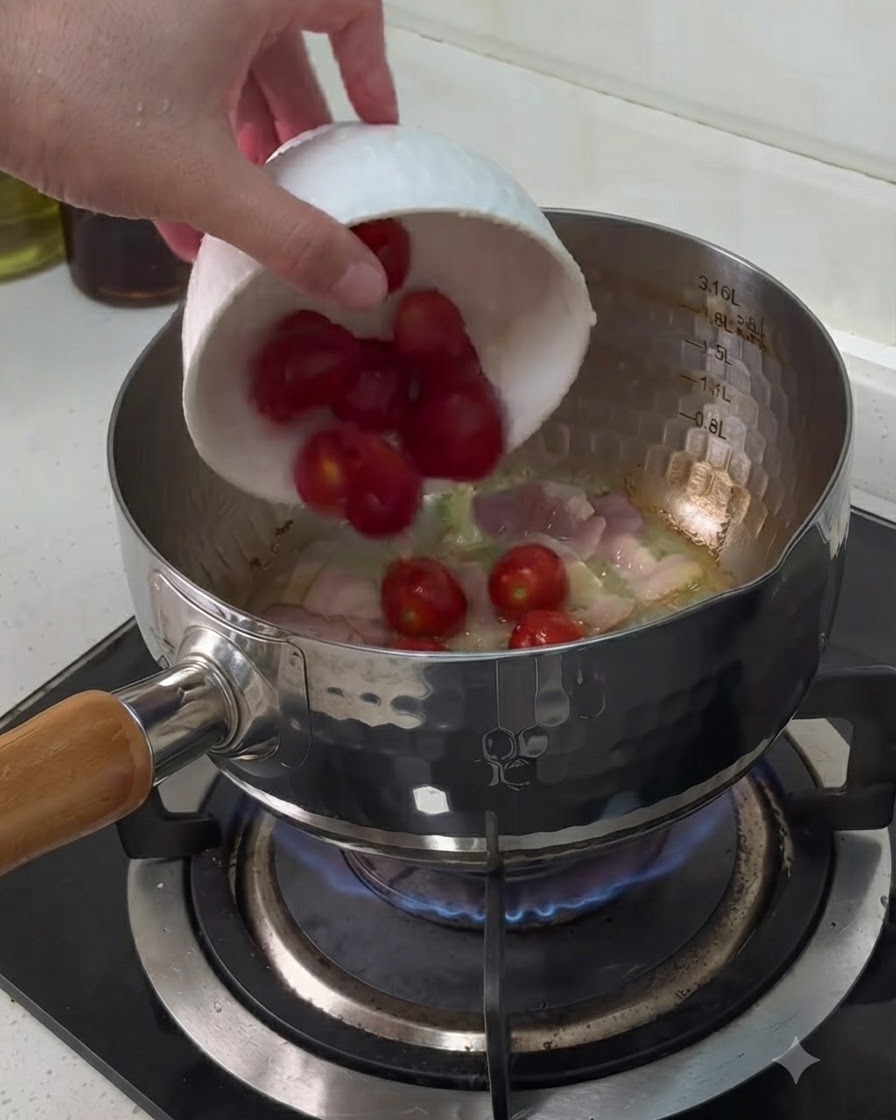 Kirschtomaten werden aus einer kleinen weißen Schüssel in einen Topf mit kochenden Baconstücken gegeben.