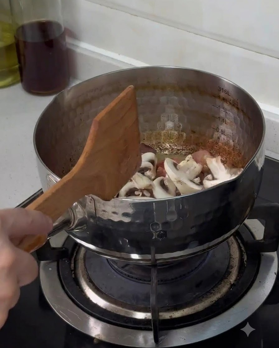 Frisch geschnittene Champignons werden in den Edelstahltopf gegeben und mit einem Holzlöffel umgerührt.