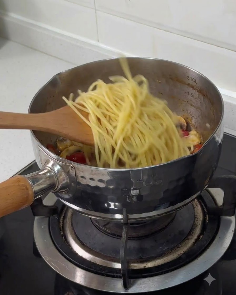 Vorgekochte Spaghetti werden mit einem Holzlöffel in einen Edelstahltopf mit anderen gekochten Zutaten gefüllt.