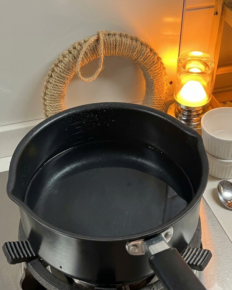 Trockene Fusilli-Pasta wird in einen Topf mit kochendem Wasser auf dem Herd gegeben.