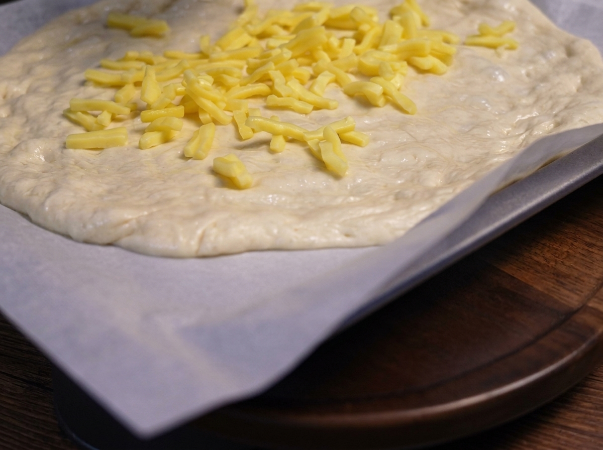 Angebratene Pilzscheiben werden auf der Käseschicht des Pizzateigs platziert.