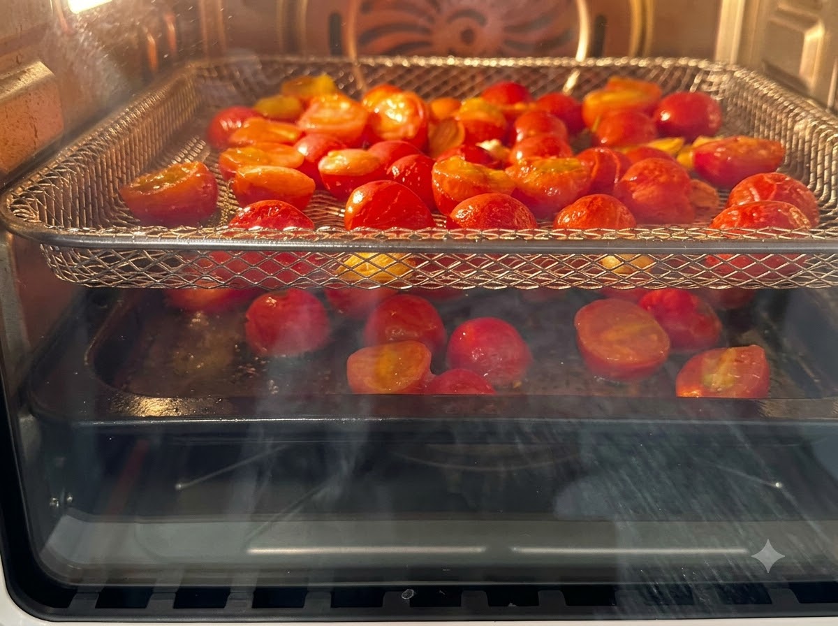 Halbierte Kirschtomaten auf den Rosten eines Heißluftfritteusen-Aufsatzes.