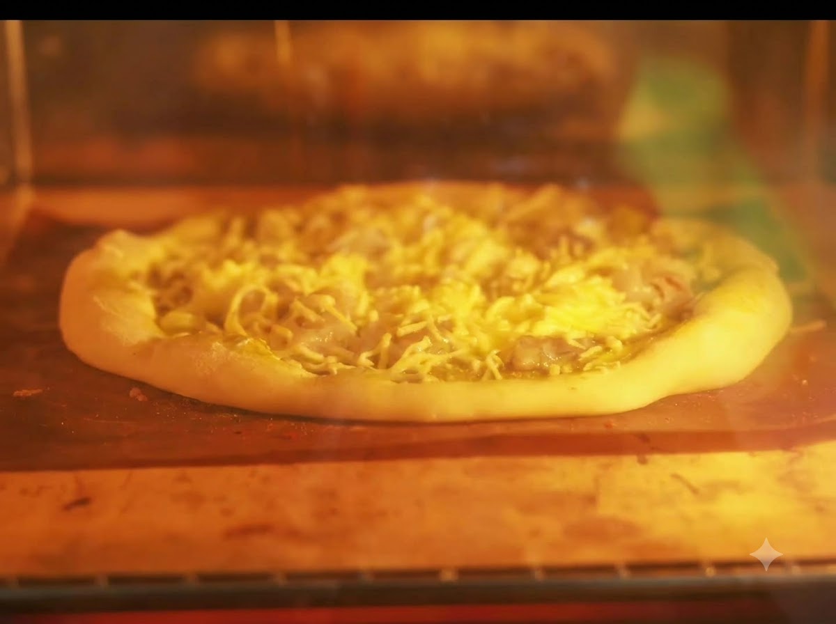 Eine Pizza backt auf einem Blech in einem beleuchteten Ofen mit glühenden Heizelementen.