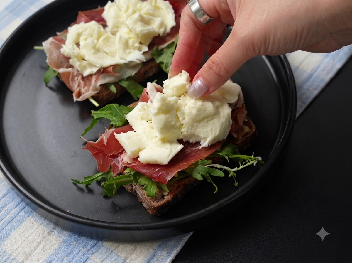 Frische Stücke zerrissener Mozzarella-Käse werden auf die Schinkenschicht des Sandwiches gelegt.